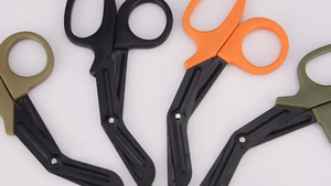 A collection of trauma shears in black, orange, and green colors, with straight blades and ergonomic handles.