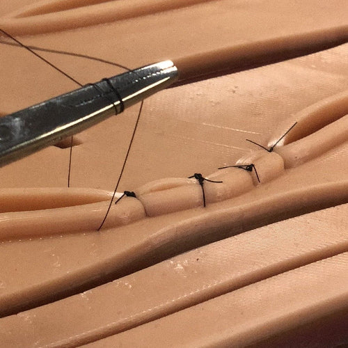 Needle driver tying a suture thread. 