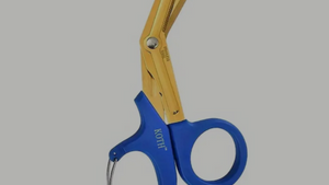 A pair of blue-handled trauma shears with a gold-colored stainless steel body and belt clip.