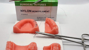 Dental suture kit including a silicone suture pad with attached tools and a box of Nylon sutures.