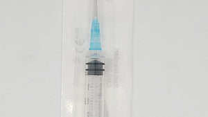 Medical syringe with needle in a clear plastic package on a gray background